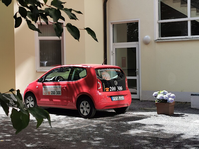 Ambulante Pflege. Dienstwagen des ambulanten Pflegepersonals vor einem Haus.