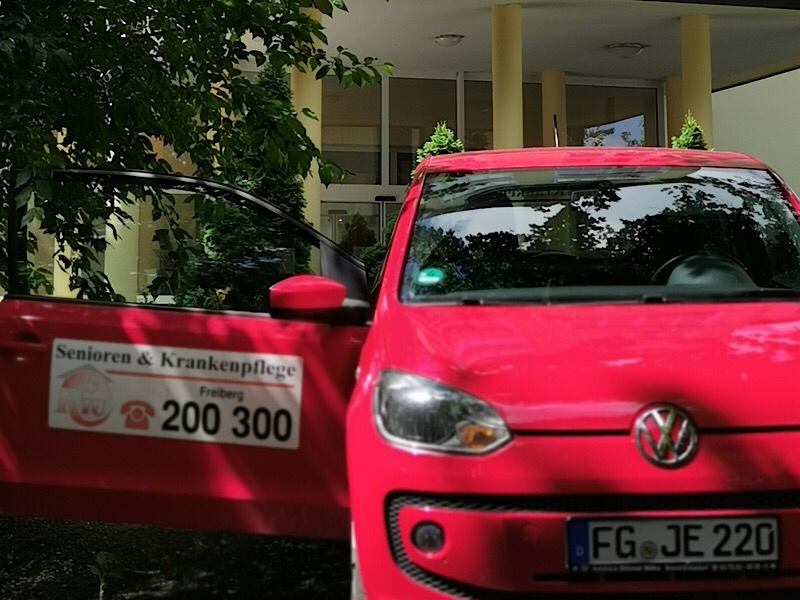 Rotes Kleinstwagen Dienstfahrzeug mit Aufschrift vor einem Gebäude im Einsatz.